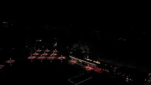 Glowing lanterns illuminate empty restaurant terrace tables beside dark coastal Stock Footage 347701071