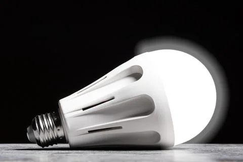 Glowing LED bulb light on the grey table on black background Stock Photos