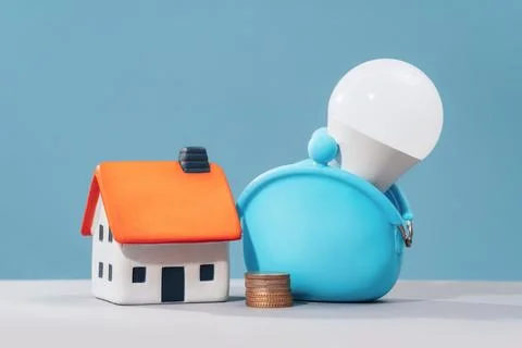 Glowing LED light bulb in coin purse and house. Saving energy Stock Photos