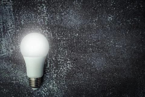 Glowing LED light bulb on dark grunge background Stock Photos
