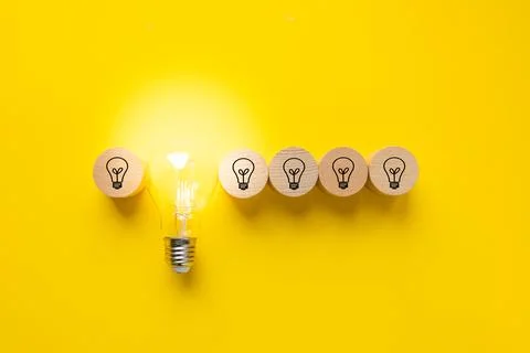 Glowing light bulb and light bulb icons on round wooden blocks.  Stock Photos