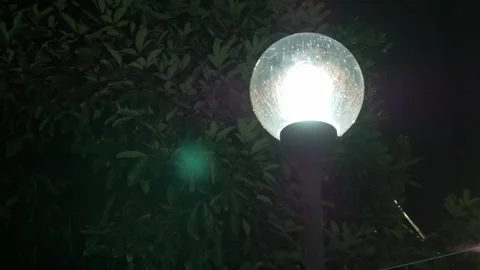 A glowing light bulb hangs from a lamp post in the darkness Video stock 298171317