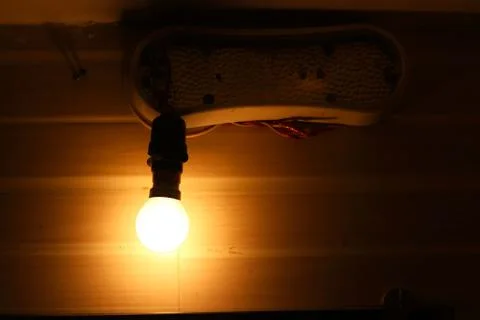 Glowing light bulb in Lamp Socket Hanging on Wire on Dark Background Stock Photos