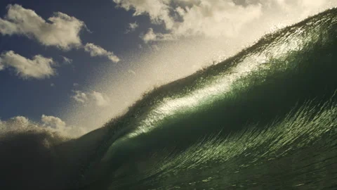 Glowing Ocean Wave Rising Beneath Bright Clouds and Sunlight Stock Footage 344033524