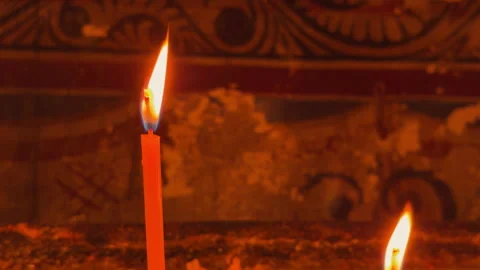 Glowing orange candle flame burning in a dim church interior Stockbeeldmateriaal 336387459