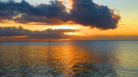 Glowing Orange Cloud Over Tropical Sea at Sunset Stock Photos