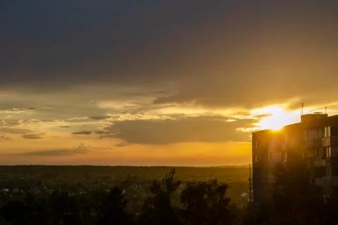 Glowing orange sun setting behind city buildings in silhouette Stock Photos