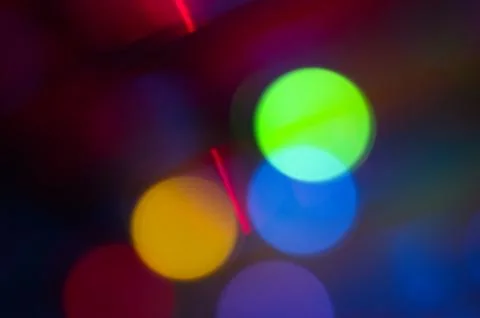 Glowing orbs of overlapping light in yellow, orange, blue and red on a dark b Stock Photos