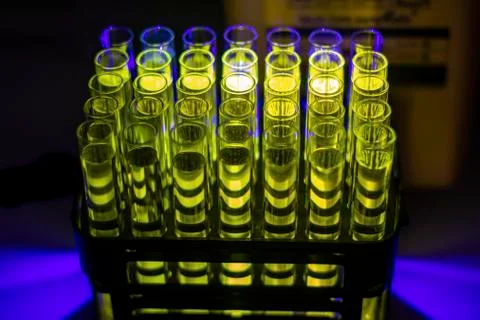 Glowing organic compound solution collected from column chromatography in mul Stock Photos