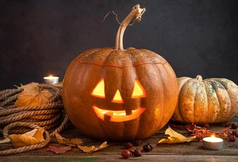 A glowing pumpkin lantern, Jack's head on a background of foliage, berries an Stock Photos