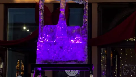 A glowing purple ice sculpture in a tree shape stands outside a restaurant at Stock Footage 345665894