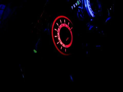 Glowing red dashboard dial illuminated in the dark interior of a car. Fotos de archivo