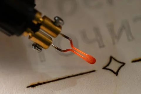 Glowing red hot tip of pyrography pen burning wood Foto stock