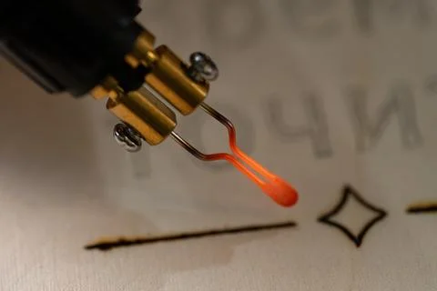 Glowing red hot tip of pyrography pen burning wood Foto stock