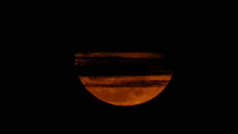 Glowing red moon behind layers of clouds Video stock 153786723