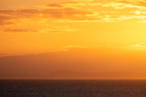 Glowing red sunset at sea with distant island at the horizon Fotos de archivo