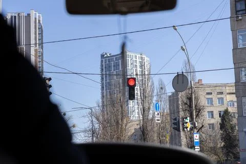 A glowing red traffic light hangs over a busy city intersection as viewed f.. Stock Photos