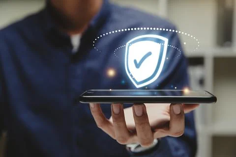 Glowing shield with a check mark on smart phone. Stock Photos