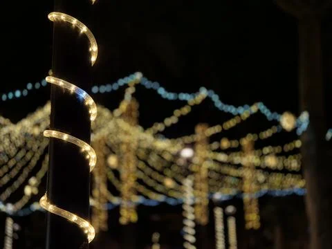 Glowing string lights wrapped around pole at night Photos