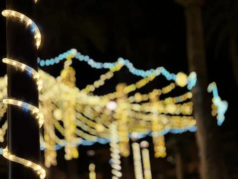 Glowing string lights wrapped around a dark pole Stock Photos