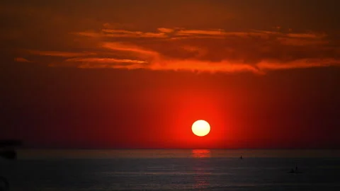 Glowing sun descending over calm ocean beneath dramatic clouds, relaxing nature Stock Footage 335489561