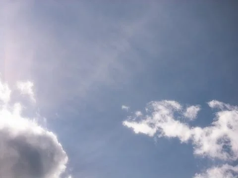 Glowing Sunlight Beside Small Clouds in a Blue Sky Stock Photos