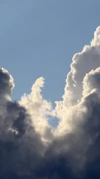 Glowing sunlit edges of dark dramatic cumulus clouds parting to reveal a Stock Photos