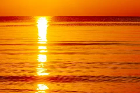 A glowing sunset over the ocean creates a striking sunburst effect Stock Photos