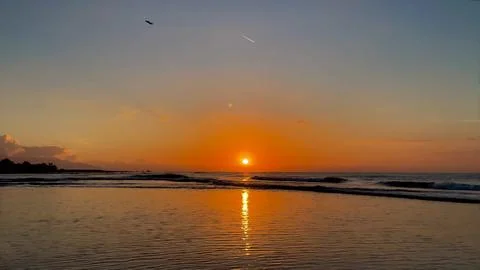 Glowing Sunset Reflection on Wet Beach Sand with Ocean Waves Stock-Fotos