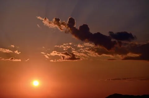 Glowing sunset sky with dramatic clouds and sunbeams 写真素材