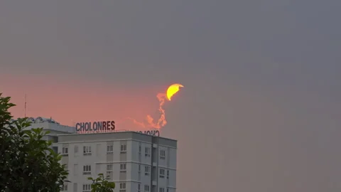 Glowing sunset sun hiding behind overcast clouds above a residential building Vídeos de archivo 339992765