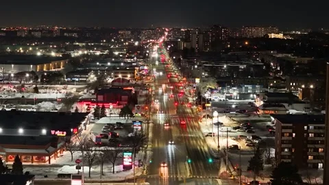 Glowing Traffic Streaming Down a Snowy City Street at Night Видео 348126121