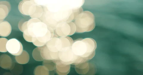 Glowing white bokeh highlights float on emerald sea water in motion Stock-Footage 326005039
