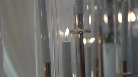 Glowing white candle placed inside a clear glass cylinder display case Stock-Footage 335270918