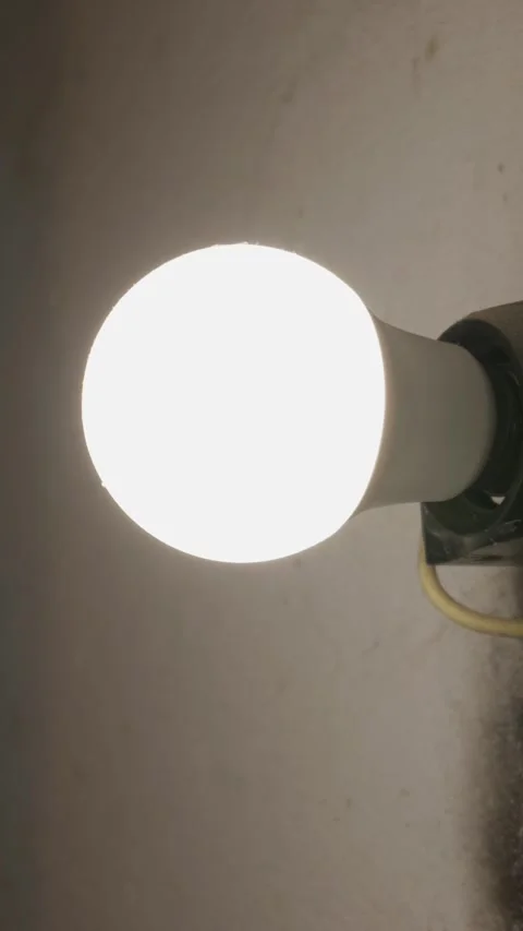 Glowing White Led Light Bulb Shining Brightly in Dim Indoor Room Stock Footage 335639249