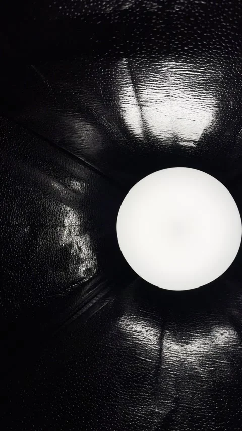 Glowing white orb illuminating textured black reflective surface in dramatic abs Stock Footage 327729462