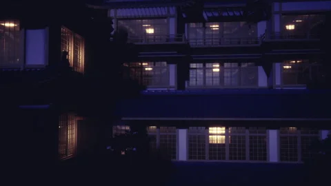 Glowing windows and night reflections highlight ancient Japanese inn scene Stock Footage 339800553