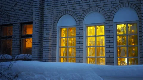 The glowing windows of the brick house are decorated with garlands . Video stock 167117780