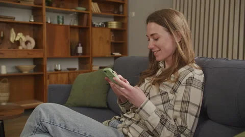 Glowing Woman Texting On Smartphone While Relaxing On Cozy Sofa At Home Stock Footage 304510651
