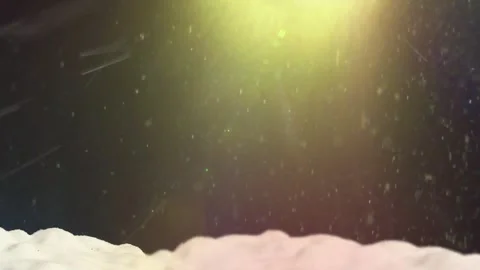 Glowing yellow light illuminates falling snowflakes over white ground surface Video stock 343842680