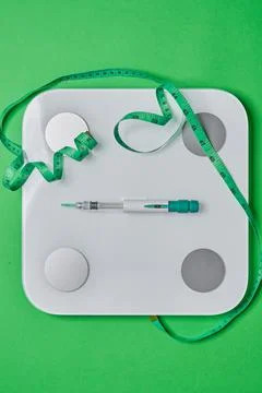 Glp-1 injection pen on scale with measuring tape Stock Photos