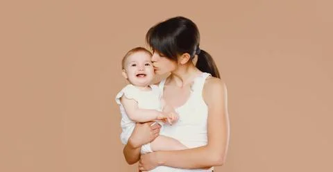 Glückliche junge Mutter hält und küsst Baby auf Studio Hintergrund Happy y Stock-Fotos