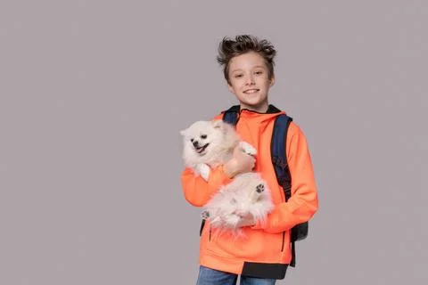 Glücklicher junger Mann, der einen pommerschen Hund in seinen Händen hält, Stock Photos