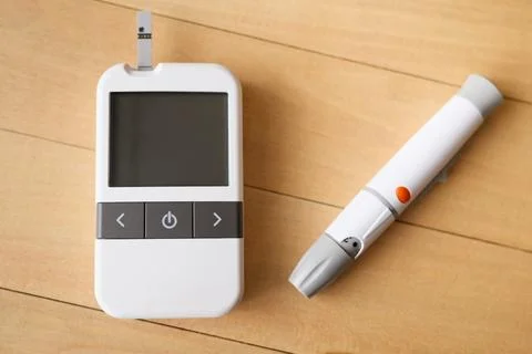 Glucometer and lancing device are placed on a light wooden background, read.. Stock Photos