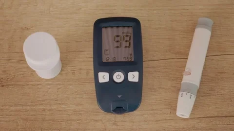 Glucometer reading of 99 mg dL shows blood sugar level on wooden table Stock Footage 346703806