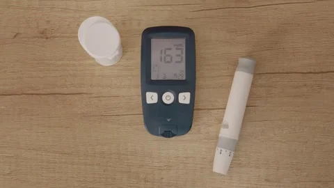 Glucometer reading shows high blood sugar level of 163 mg dL on wooden table Stock Footage 346703653
