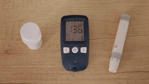 Glucometer shows high reading of 136 mg dL on wooden table near diabetes tools Stock Footage 346703829