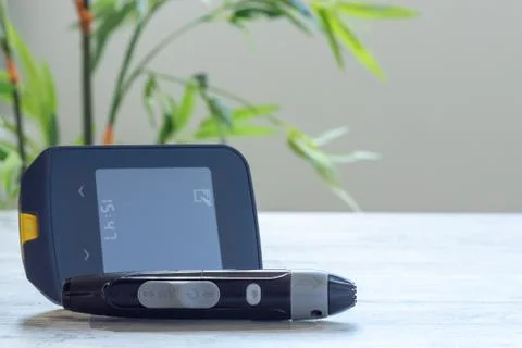 Glucometer on table with plants in the background Stock Photos