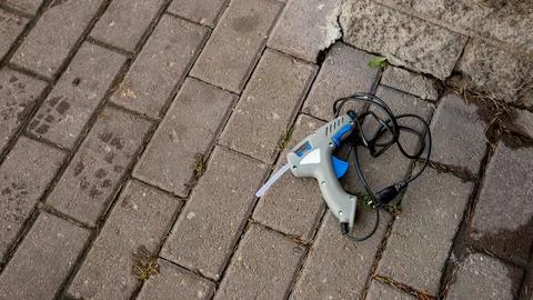 Glue gun on a paved stone surface. Craft tool for repair, construction 스톡 사진