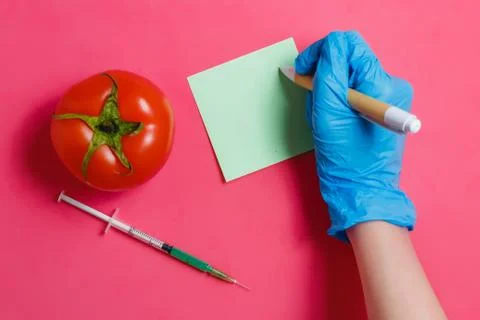 GMO Scientist Make Note, Green Liquid in Syringe,Red Tomato - Genetically Stock Photos